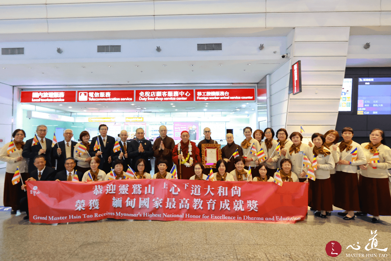 靈鷲山護法會委員於機場迎接心道法師返台，手持布條祝賀緬甸國家最高教育成就獎並合影留念