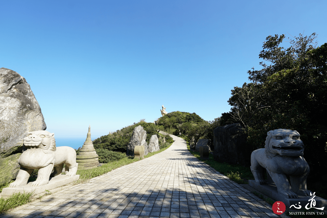 靈鷲山石獅守護的山徑通向遠方菩薩像與海天一色，象徵心道法師教導的佛法是引領眾生走向光明的道路